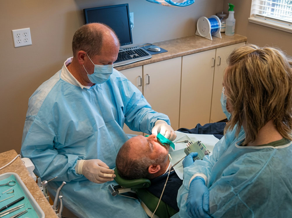 Dentist and assistant treating a patient at the Food & Care Coalition free dental clinic in Provo, Utah